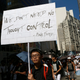 A protester holds a placard as thousands of people march in a down town street in Hong Kong Sunday, July 29, 2012.to protest the looming introduction of Chinese patriotism classes.